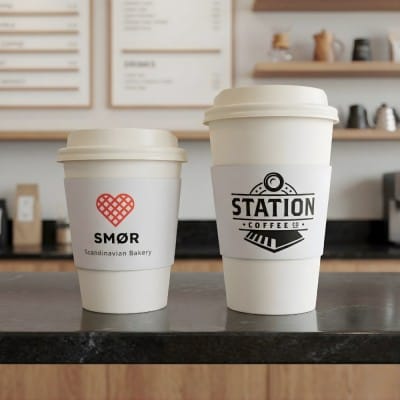 custom paper coffee cups with corrugated sleeves featuring SMØR and Station Coffee branding on café counter